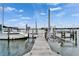 View down the boat dock with boat lift, surrounded by peaceful water and blue skies at 1335 Jumana Loop, Apollo Beach, FL 33572