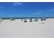 Sandy beach with beach umbrellas and shallow blue ocean view at 13500 Gulf Blvd # 505, Madeira Beach, FL 33708