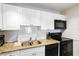 Close-up of kitchen showcasing granite countertops, stainless steel sink, and black appliances at 13500 Gulf Blvd # 505, Madeira Beach, FL 33708