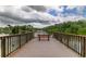 Scenic lake view from a wooden pier, featuring a bench for relaxation and enjoying the tranquil water and lush green surroundings at 136 Sycamore Ln # C, Oldsmar, FL 34677