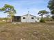 Rear of home featuring screened porch, white paint, chimney, and large yard at 15630 Camrose Ave, Spring Hill, FL 34610