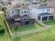 Aerial view of the backyard featuring a screened-in patio, a well-maintained lawn, and a white picket fence at 29011 Trevi Pl, Wesley Chapel, FL 33543