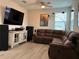 Large living room featuring a sectional couch, ceiling fan, media center, laminate flooring, and natural light at 29011 Trevi Pl, Wesley Chapel, FL 33543