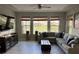 Cozy living room with tile floors, tray ceiling, ceiling fan, large windows, and comfortable sectional sofa at 29011 Trevi Pl, Wesley Chapel, FL 33543