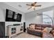 Cozy living room with ceiling fan, brown sectional, television, and modern lamp at 29011 Trevi Pl, Wesley Chapel, FL 33543
