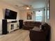 Comfortable living room featuring a sectional couch, media center, ceiling fan, and laminate flooring at 29011 Trevi Pl, Wesley Chapel, FL 33543