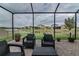 Screened patio with brick floor, view of backyard, furniture, and pond in the background at 29011 Trevi Pl, Wesley Chapel, FL 33543