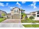 Charming two-story home featuring a three-car garage, manicured lawn, and tropical landscaping at 3027 Marine Grass Dr, Wimauma, FL 33598