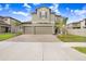 Attractive two-story home featuring a brick driveway, three-car garage, and carefully manicured landscaping at 3027 Marine Grass Dr, Wimauma, FL 33598