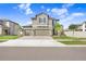 Inviting two-story home with a three-car garage, beautiful landscaping, and a well-maintained lawn at 3027 Marine Grass Dr, Wimauma, FL 33598