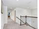 Bright hallway with gray carpet, white walls, and elegant dark wood railing at 3027 Marine Grass Dr, Wimauma, FL 33598