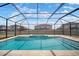 Screened-in pool with blue water and surrounding pavers and neighboring homes at 30653 Parrot Reef Ct, Wesley Chapel, FL 33545