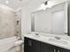 Bathroom with dual sinks, black cabinets, and tiled shower at 3201 S Manhattan Ave, Tampa, FL 33629
