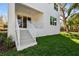 Exterior of a white two-story home with green grass, white staircase, and sliding glass doors at 3201 S Manhattan Ave, Tampa, FL 33629