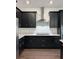 Close up of kitchen boasts dark cabinets, stainless steel appliances and range hood, and white countertop at 3201 S Manhattan Ave, Tampa, FL 33629
