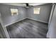 A bright bedroom features wood-look floors, ceiling fan, and two windows at 3820 E Lakeshore Dr, Tampa, FL 33604