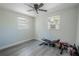 A neutral bedroom features wood-look floors, a ceiling fan, and two windows at 3820 E Lakeshore Dr, Tampa, FL 33604