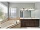 Bright bathroom with soaking tub and double sink vanity with dark cabinets, providing ample space at 410 Manns Harbor Dr, Apollo Beach, FL 33572