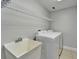Laundry room with white washer, dryer, utility sink, and shelving at 410 Manns Harbor Dr, Apollo Beach, FL 33572