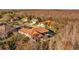 An aerial view of an estate home with a red tile roof, screened pool, and mature trees at 5204 Avenue La Crosse, Lutz, FL 33558