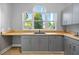 Charming laundry room featuring gray cabinets, butcher block countertop, sink and large window at 5204 Avenue La Crosse, Lutz, FL 33558