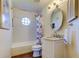 Charming bathroom features a shower and tub combo with a vintage round window and updated vanity at 701 Lighthouse Dr, Tarpon Springs, FL 34689