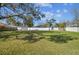 Large grassy backyard with mature trees, partially shaded and enclosed by a white fence at 8025 N Gomez Ave, Tampa, FL 33614