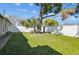 Green backyard with grass and a white fence with trees and partial shade at 8025 N Gomez Ave, Tampa, FL 33614