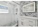 Modern bathroom featuring mosaic tile accent wall, glass enclosed shower, and updated vanity at 8025 N Gomez Ave, Tampa, FL 33614