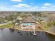 Aerial view of a community pool, lake, dock, tennis courts and clubhouse surrounded by mature landscaping and trees at 9402 Stonewall Ln, New Port Richey, FL 34655
