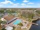 Aerial view of community pool with lounge chairs, a hot tub, palm trees, tennis courts, and lake access at 9402 Stonewall Ln, New Port Richey, FL 34655