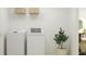 Bright laundry room features a white washer and dryer, stylish decor, and a functional storage shelf at 10212 Gentle Rain Dr, Land O Lakes, FL 34638