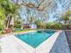 Sparkling pool with lush tropical landscaping and mature shade trees creates a serene backyard oasis at 1108 Commodore St, Clearwater, FL 33755