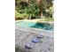 Backyard view of a refreshing pool with stepping stones leading to two Adirondack chairs under the trees at 1108 Commodore St, Clearwater, FL 33755