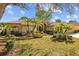 Beautiful home with a well-manicured lawn, lush tropical landscaping, and a red tile roof on a sunny day at 1213 Halifax Ct, Tarpon Springs, FL 34688