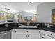 Modern kitchen sink with black granite countertop and white cabinets overlooking living area at 1213 Halifax Ct, Tarpon Springs, FL 34688