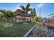 Tropical backyard featuring a tiki hut, lush palm trees, and a landscaped waterfront view, perfect for relaxation at 13429 Lisa Dr, Hudson, FL 34667