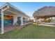 Backyard featuring a thatched palapa, a hot tub, and a mural of sea life painted on the side of the home at 13429 Lisa Dr, Hudson, FL 34667