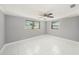 This bedroom has a ceiling fan, white-tile floors, base-molding, and two windows at 13429 Lisa Dr, Hudson, FL 34667