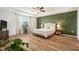 Bedroom featuring a tray ceiling, green accent wall, and wood-look flooring at 14330 Fissore Blvd, Wimauma, FL 33598