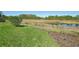Lush green backyard with well-manicured lawn, garden, and a scenic view of the pond and trees at 16407 Frehley Run, Land O Lakes, FL 34638