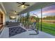 Screened lanai with comfortable seating area, ceiling fans, and views of the green backyard at 16407 Frehley Run, Land O Lakes, FL 34638