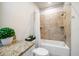Charming bathroom featuring a granite-topped vanity and a tiled shower-tub combination with built-in shelves at 1986 Lake Ridge Blvd, Clearwater, FL 33763