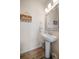 Cozy powder room with pedestal sink, decorative mirror, stylish decor and wood-look flooring at 1986 Lake Ridge Blvd, Clearwater, FL 33763