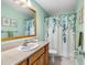 Well-lit bathroom with a large mirror, decorative shower curtain, and neutral color scheme at 2251 Glenmoor N Rd, Clearwater, FL 33764