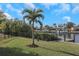 Beautiful backyard with a grassy lawn, mature landscaping, and a waterfront view with private dock at 4054 Rocky Shores Dr, Tampa, FL 33634