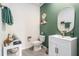 Stylish half bathroom with green accent wall, vanity, and decorative fixtures at 5640 Wandering Willow Dr, Wesley Chapel, FL 33545