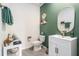 Stylish powder room featuring a custom vanity, and a modern design with contrasting green accent wall at 5640 Wandering Willow Dr, Wesley Chapel, FL 33545