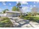 Wide driveway leading to an attached garage with mature landscaping at 8704 Thornwood Ln, Tampa, FL 33615