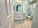 Charming bathroom with stylish vanity, glass sink, and a refreshing tropical-patterned shower curtain at 1 Boca Ciega Point Blvd # 213, St Petersburg, FL 33708